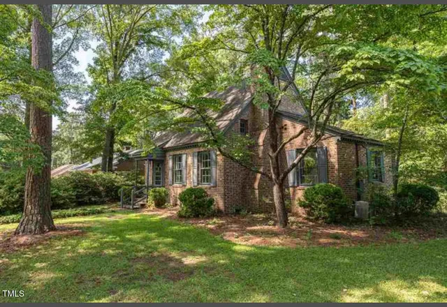 a backyard of a house with plants and large tree