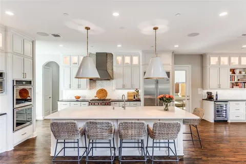 a kitchen with stainless steel appliances granite countertop a kitchen island a stove a sink a dining table and chairs with wooden floor