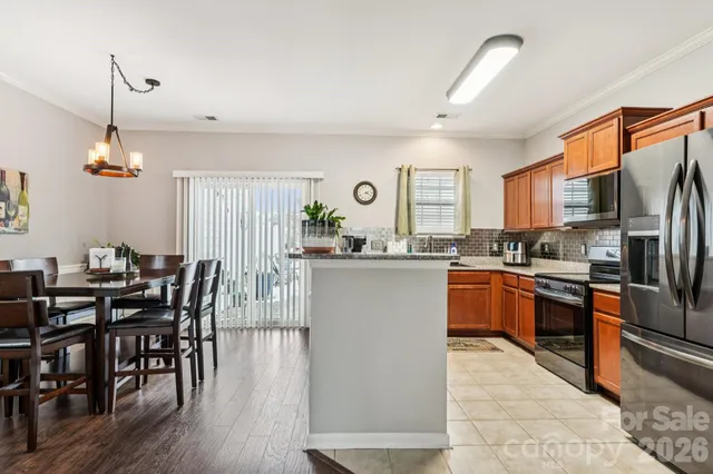 a kitchen with stainless steel appliances granite countertop a refrigerator a stove a sink dishwasher a dining table and chairs with wooden floor