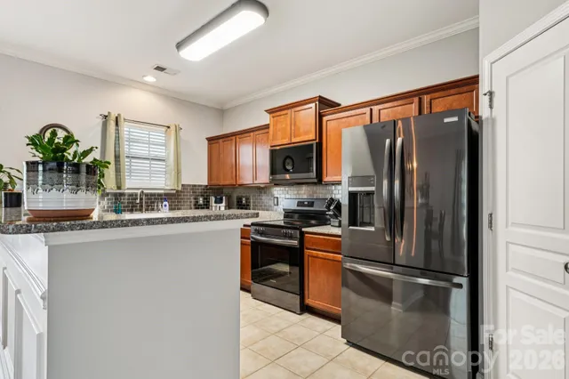 a kitchen with stainless steel appliances granite countertop a refrigerator a stove a sink and a microwave