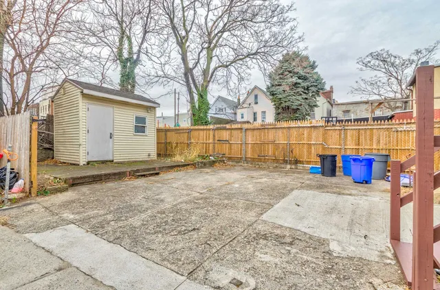a view of backyard with large tree and wooden fence