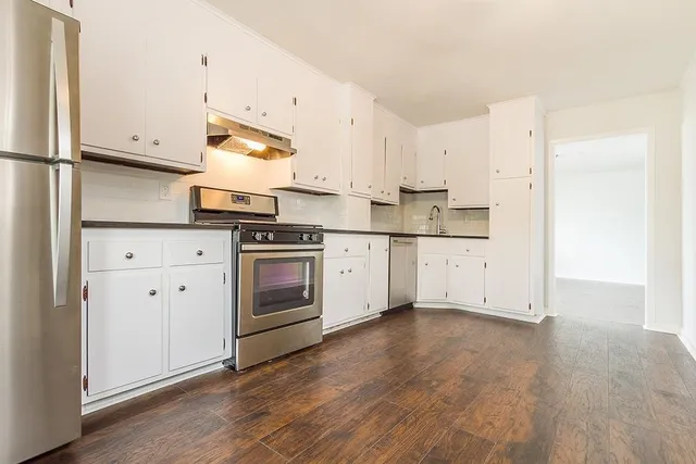 a kitchen with stainless steel appliances white cabinets and wooden floors