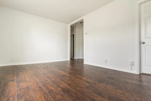 a view of an empty room with wooden floor and closet