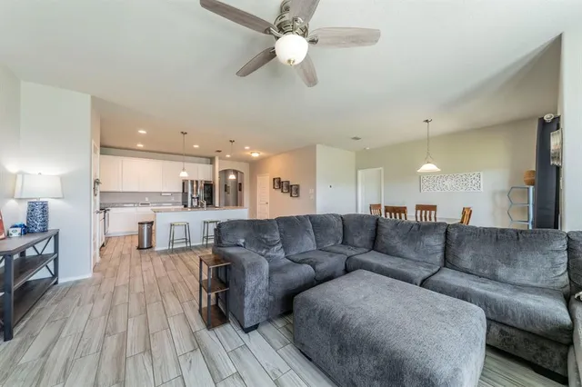 a living room with couches and kitchen view with wooden floor
