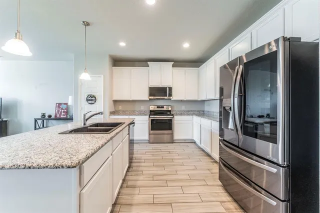a kitchen with granite countertop a refrigerator and a sink