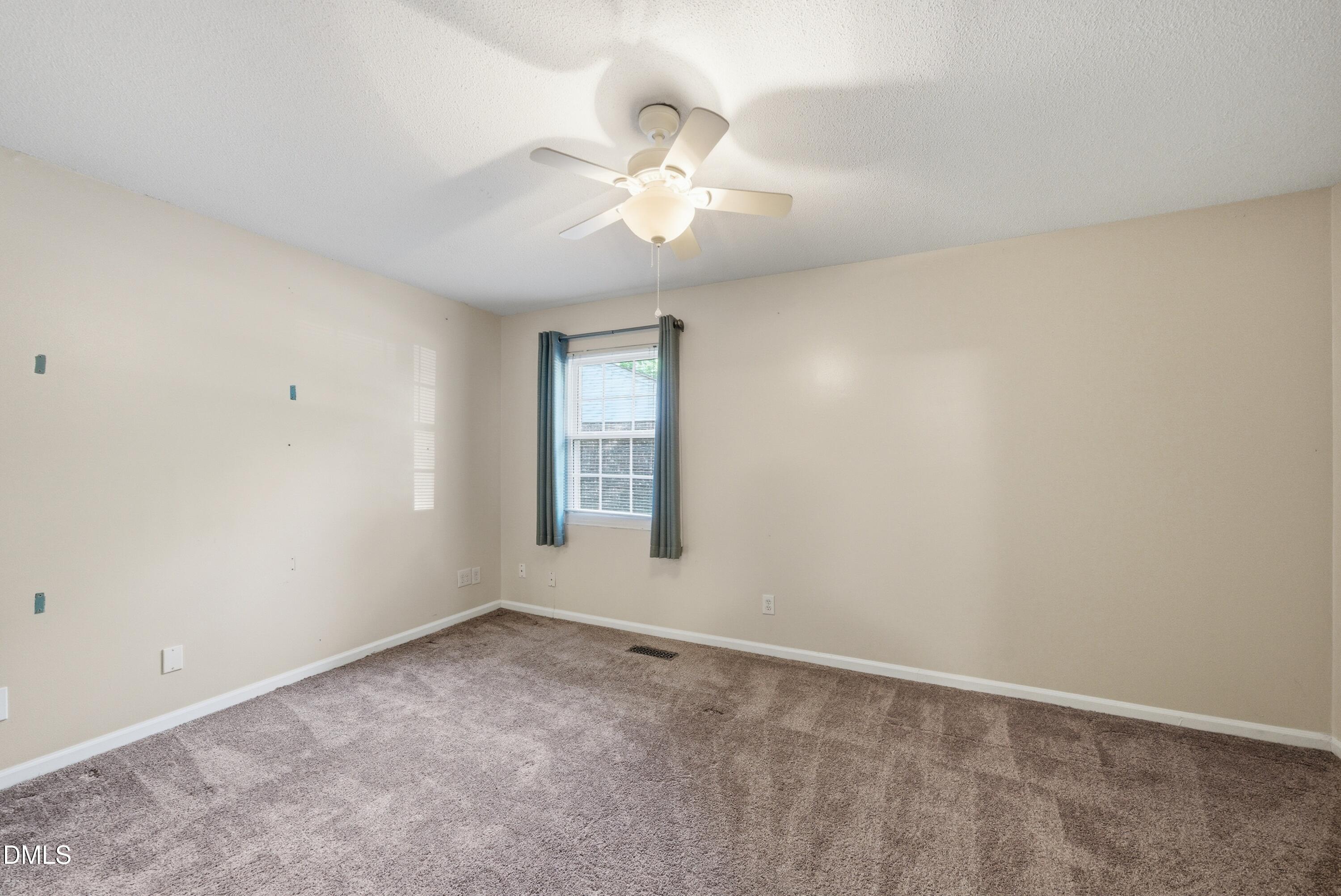 6355 New Market Way Raleigh, NC 27615 - Photo 26 of 30 an empty room with a chandelier fan and windows