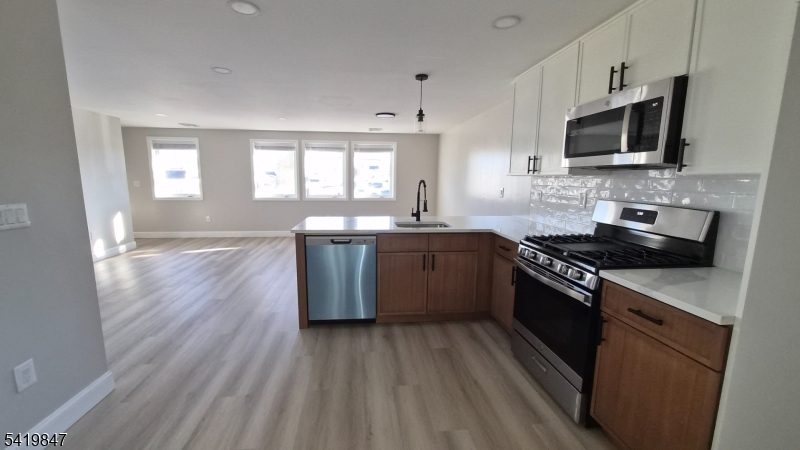 515 Maple Avenue, Unit 2 Rahway, NJ 07065 - Photo 1 of 13 a large kitchen with stainless steel appliances granite countertop a stove a sink dishwasher and a microwave oven with wooden floor