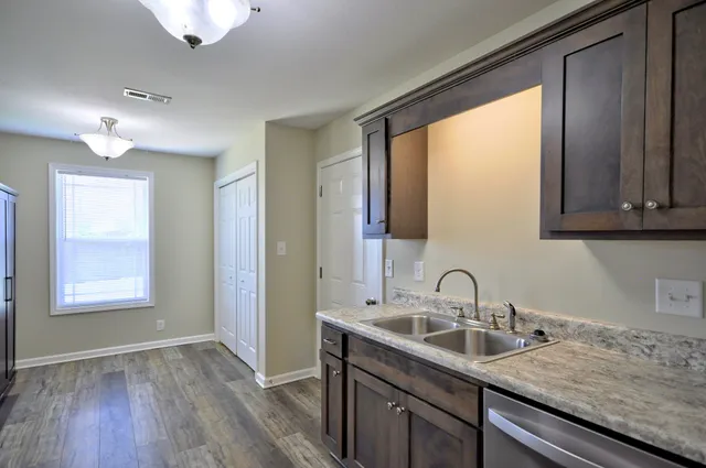 a kitchen with stainless steel appliances granite countertop a refrigerator a sink and wooden floors