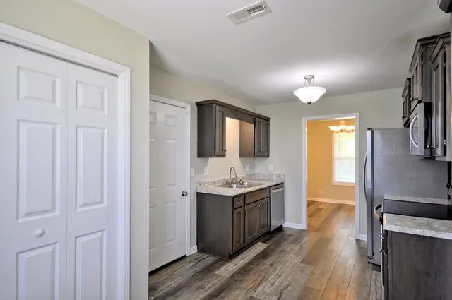 a kitchen with stainless steel appliances granite countertop a refrigerator a stove and a sink with wooden floor