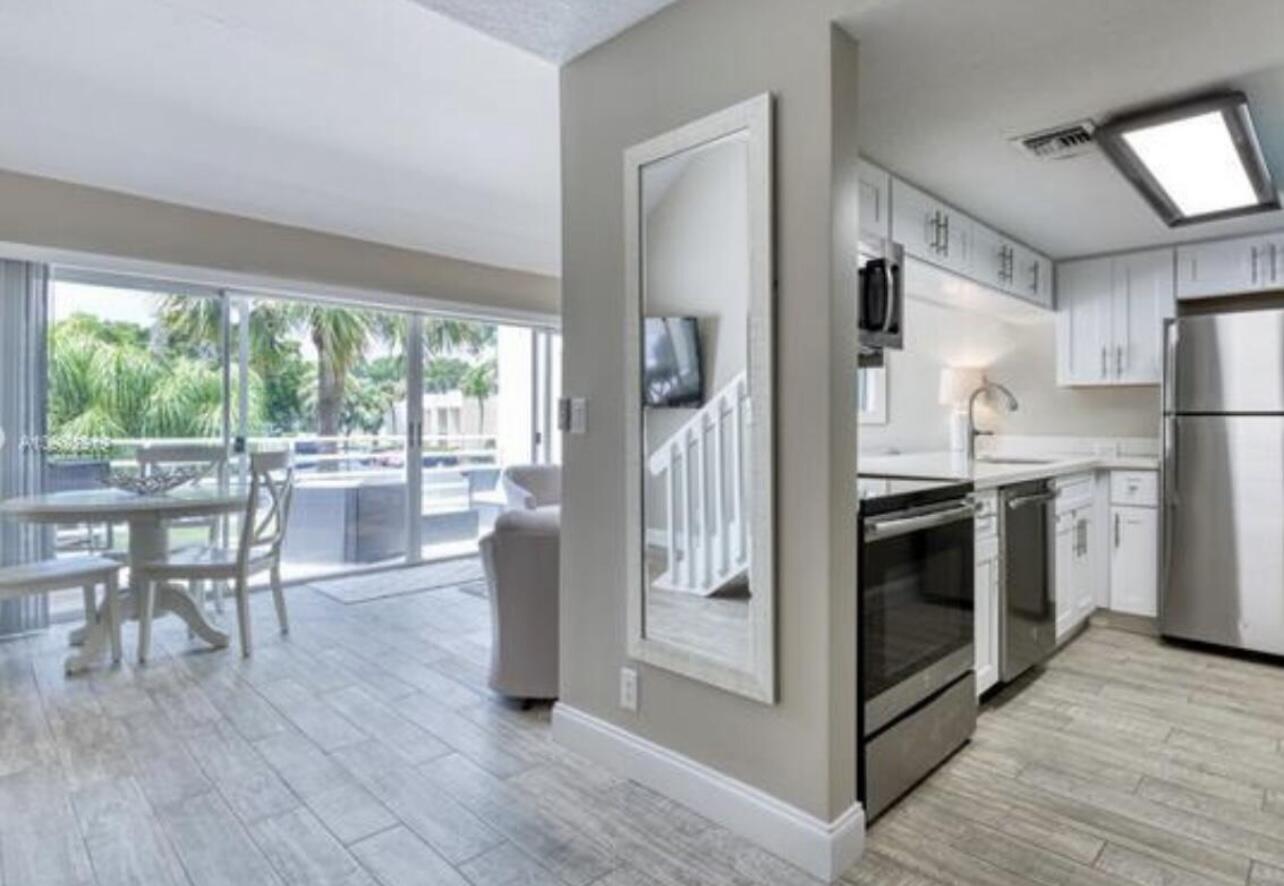 1605 Highway 1, Unit M2202 Jupiter, FL 33477 - Photo 1 of 19 a kitchen with stainless steel appliances a stove a refrigerator a dining table and chairs with wooden floor