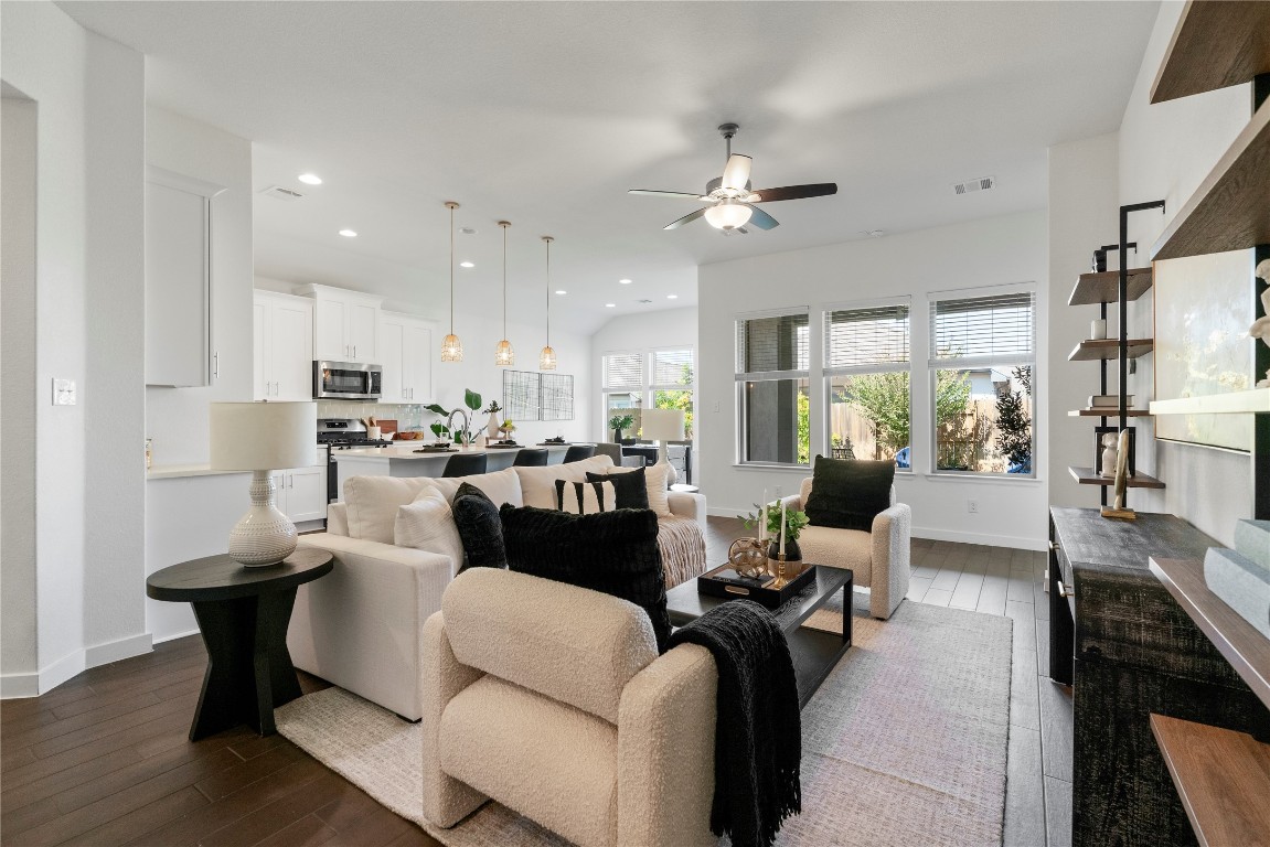 a living room with furniture kitchen view and a chandelier