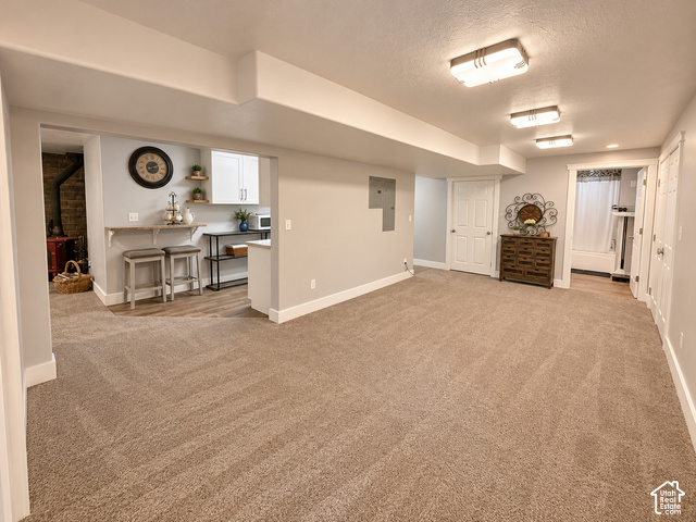 1750 West 4100 North Helper, UT 84526 - Photo 36 of 50 Expansive carpeted area with recessed lighting, complemented by a compact kitchen featuring white cabinetry and wood-finish flooring