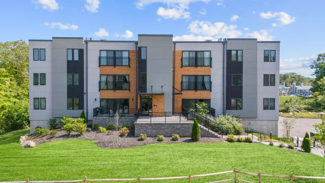a front view of a residential apartment building with a yard and plants