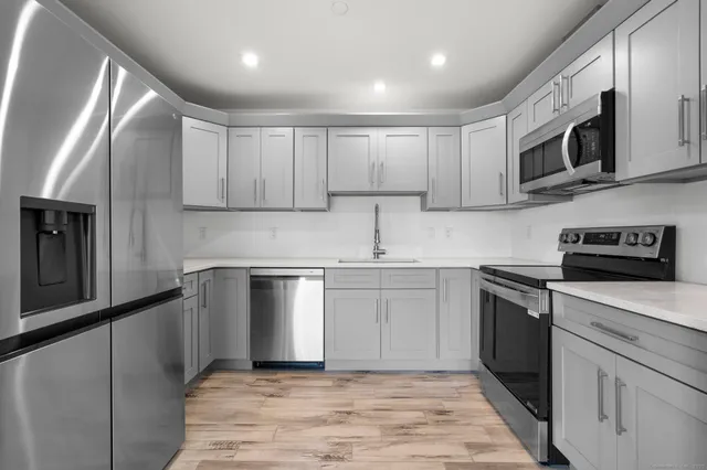 a kitchen with stainless steel appliances granite countertop a sink and a stove top oven