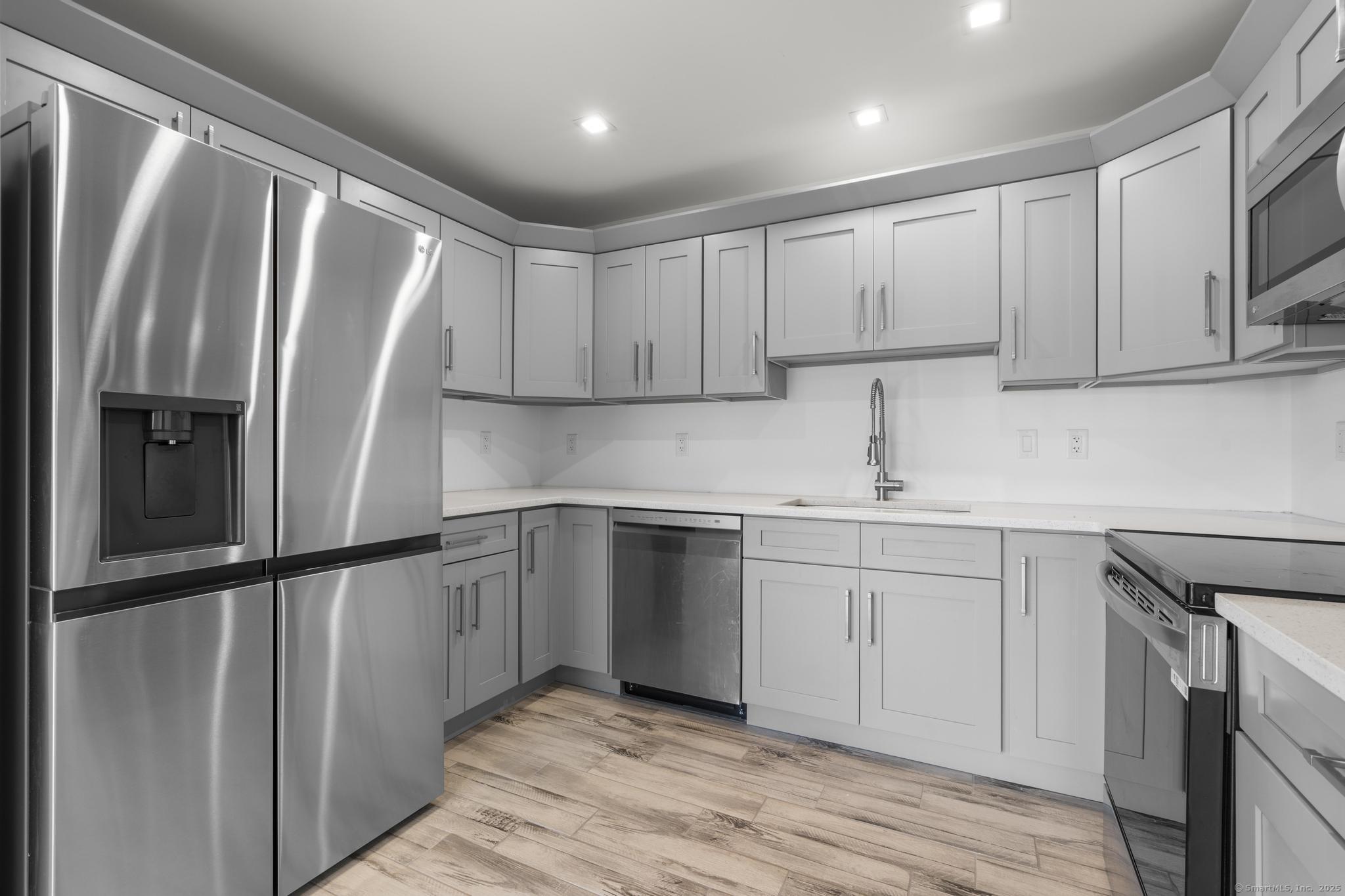 245 East Main Street, Unit 2 Branford, CT 06405 - Photo 22 of 40 a kitchen with granite countertop a refrigerator sink and cabinets