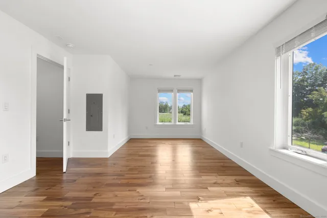 an empty room with wooden floor and windows