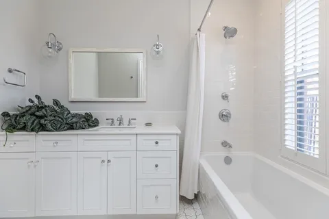 a bathroom with a bathtub a sink a window and a shower