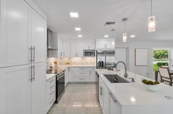 a kitchen with white cabinets and sink