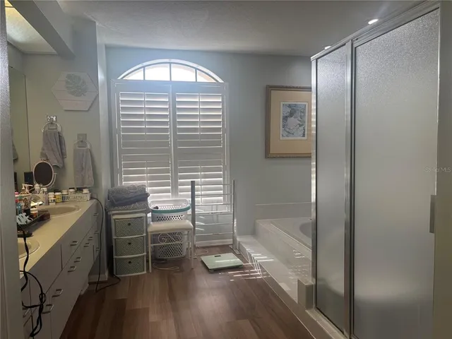 a bathroom with a sink a large mirror a bathtub and next to a window