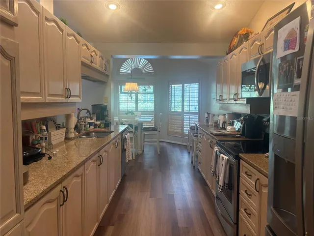 a kitchen with stainless steel appliances granite countertop lots of counter top space and wooden floor