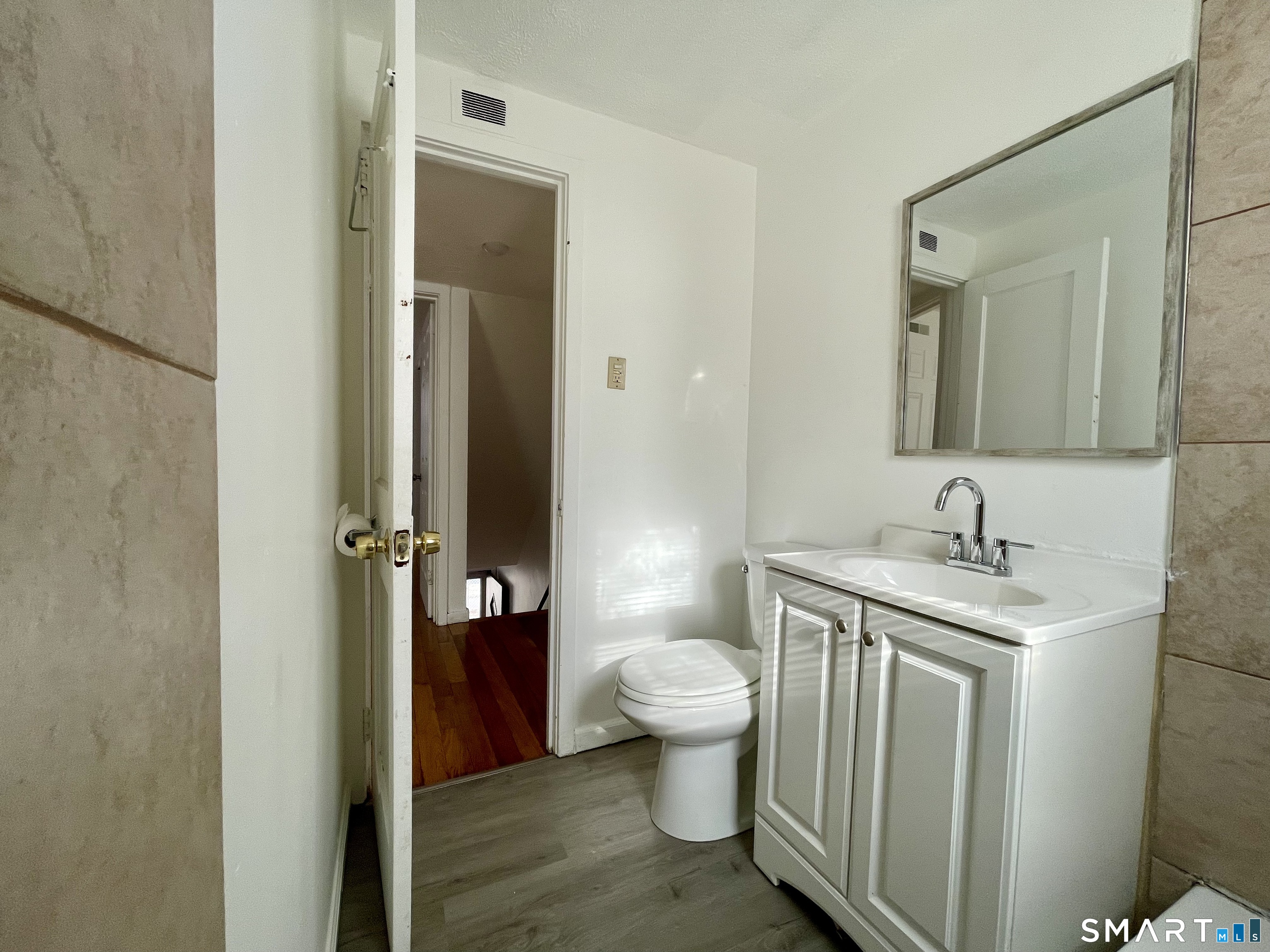 35 Baltic Street Hartford, CT 06112 - Photo 8 of 18 a bathroom with a granite countertop toilet a sink and a mirror