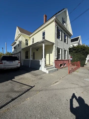 a view of a white building among the street with cars