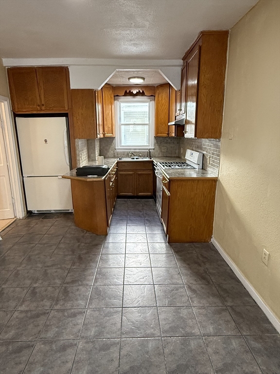 213 Concord Street, Unit 1 Lowell, MA 01852 - Photo 6 of 12 a kitchen with stainless steel appliances granite countertop a stove a sink and a refrigerator