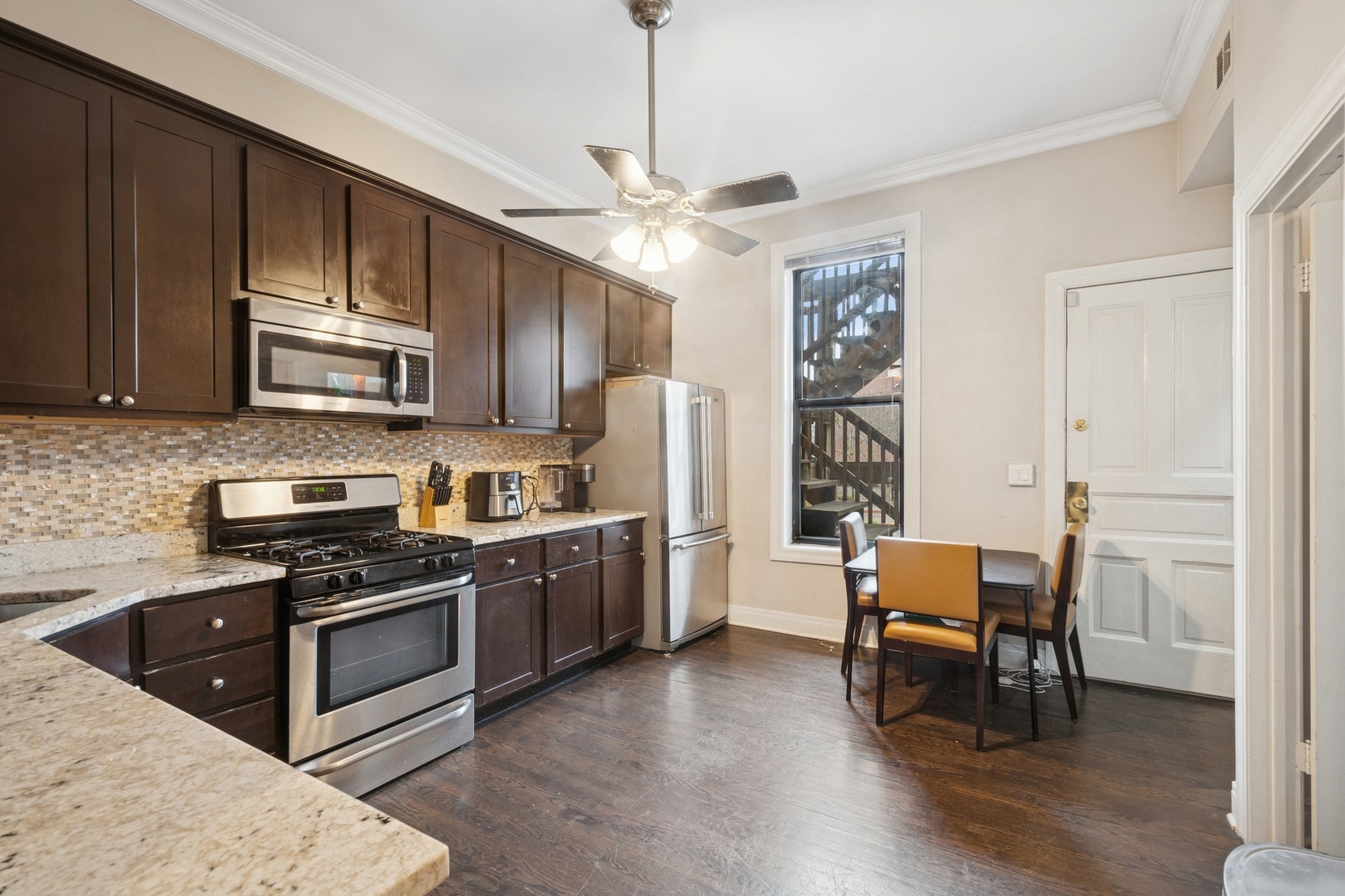 1302 North Cleveland Avenue, Unit 2 Chicago, IL 60610 - Photo 6 of 12 a kitchen with stainless steel appliances granite countertop a stove top oven a sink dishwasher a dining table and chairs with wooden floor