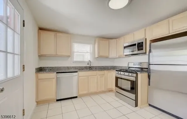 a kitchen with granite countertop white cabinets stainless steel appliances and a sink