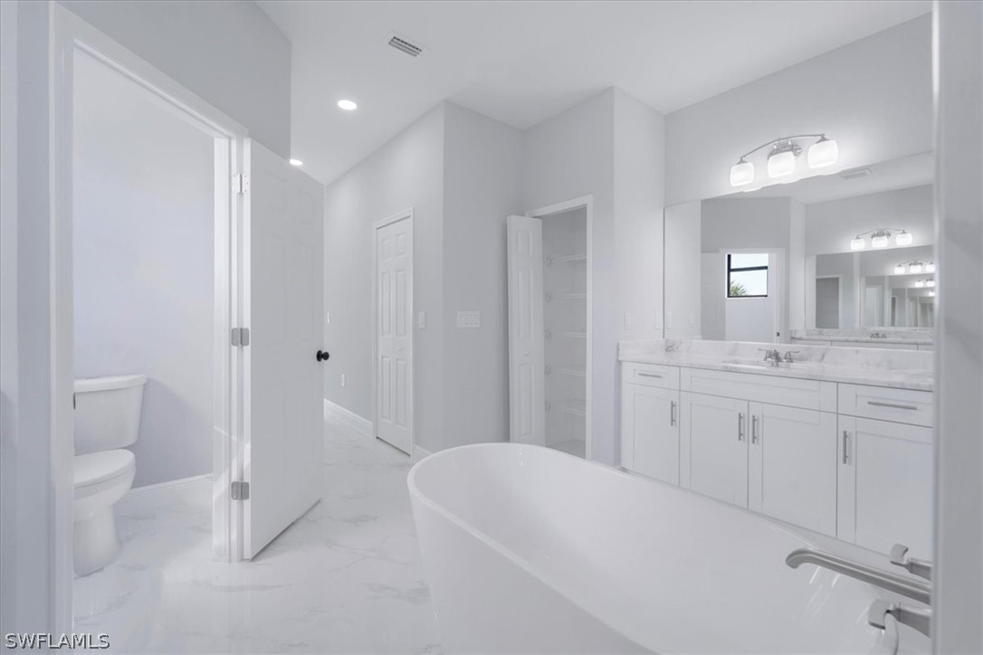 3915 20th Street Southwest Lehigh Acres, FL 33976 - Photo 32 of 50 a spacious bathroom with a granite countertop sink a toilet and a large mirror