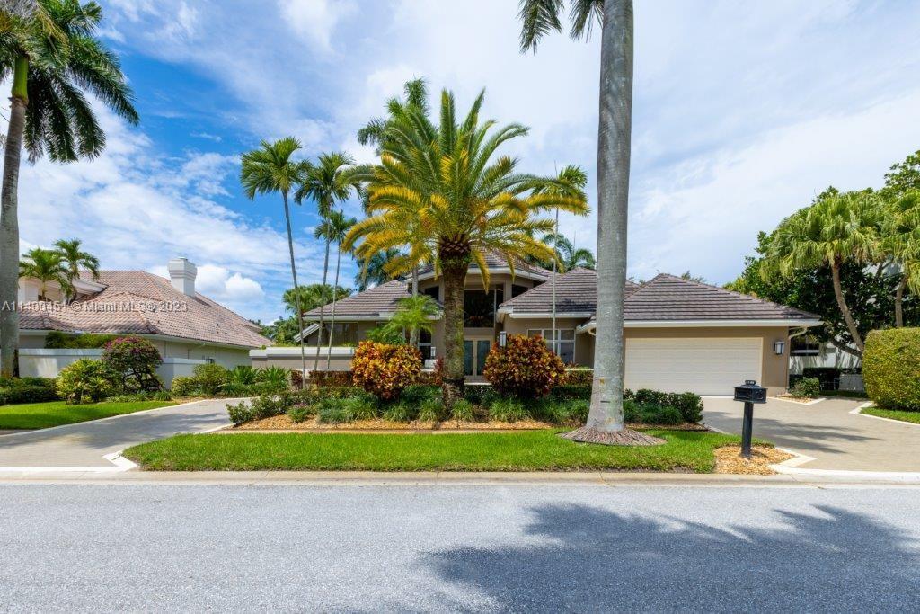 a view of a house with a yard and palm trees