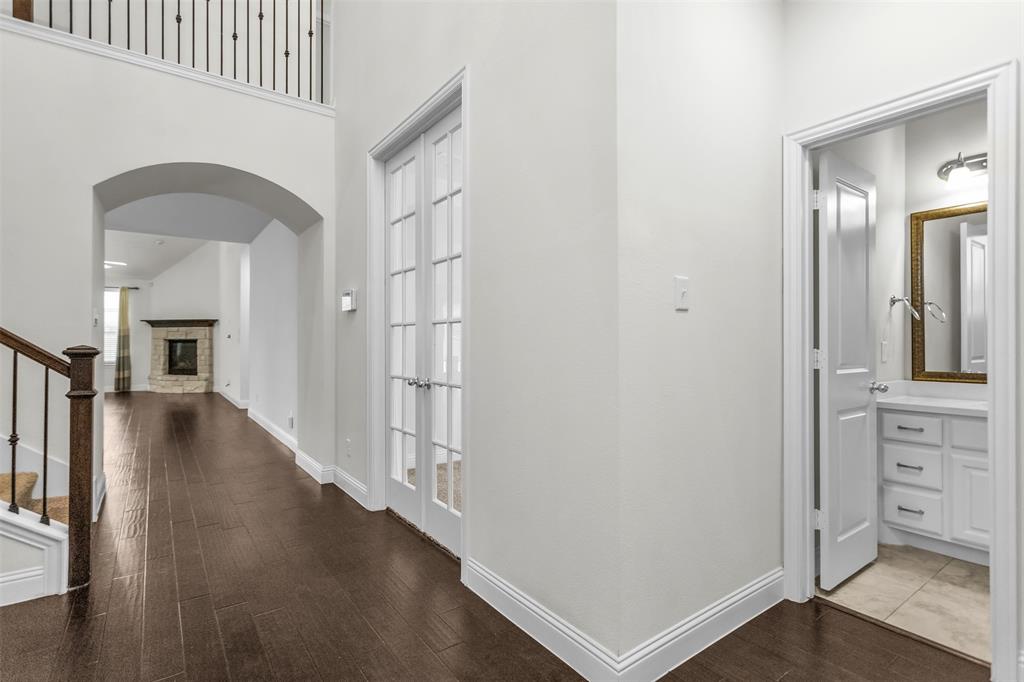 15713 Canyon Ridge Prosper, TX 75078 - Photo 4 of 38 Hallway featuring wood-finish flooring, an arched doorway, and French doors