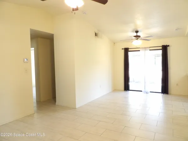 an empty room with chandelier fan and windows