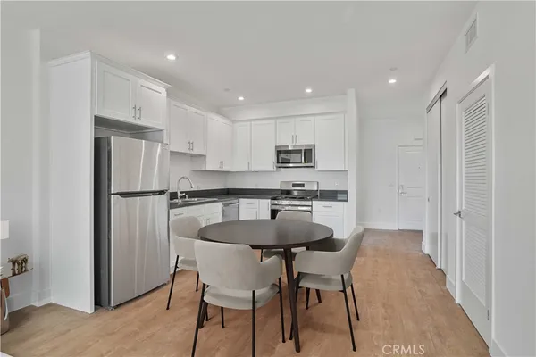 a kitchen with stainless steel appliances granite countertop a dining table chairs refrigerator sink and cabinets