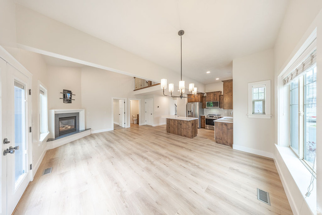 2169 Orchard Pines Loop East Bountiful, UT 84010 - Photo 2 of 32 Spacious open-concept interior featuring light wood-finish flooring, a white-mantled fireplace with a dark surround, and vaulted ceilings