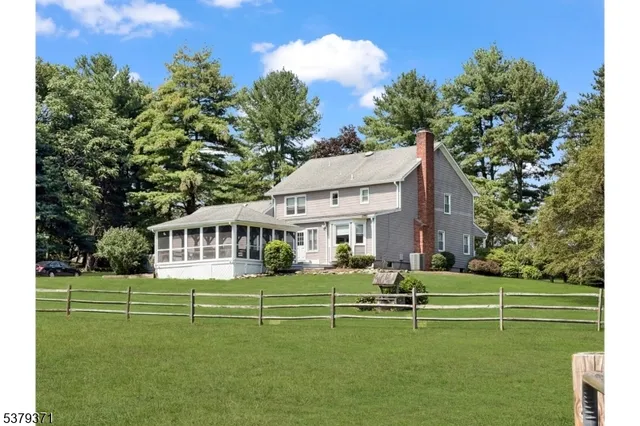 a view of a two chairs in a big yard with large trees