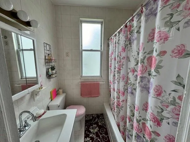 a bathroom with a toilet sink and shower curtain