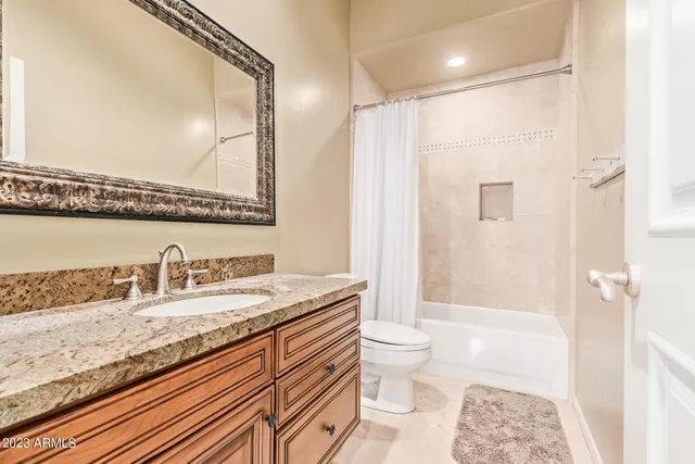 a bathroom with a granite countertop sink a toilet and shower