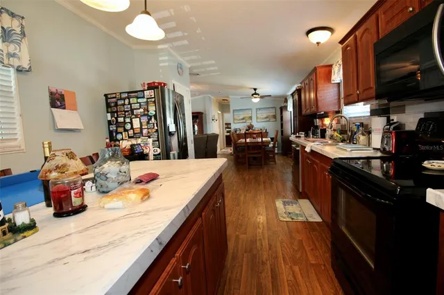 a kitchen with granite countertop stainless steel appliances wooden floors and wooden cabinets