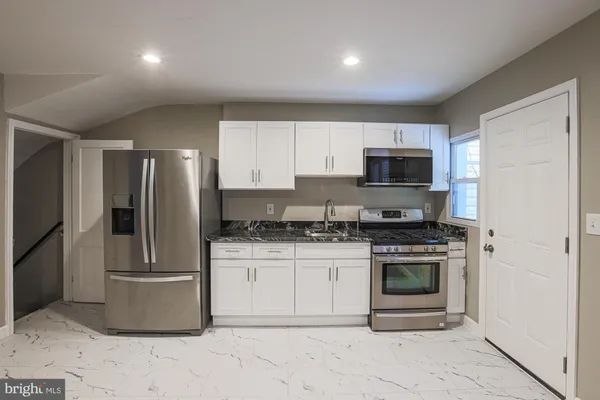 a kitchen with stainless steel appliances granite countertop a stove a refrigerator a sink a microwave a counter top and cabinets