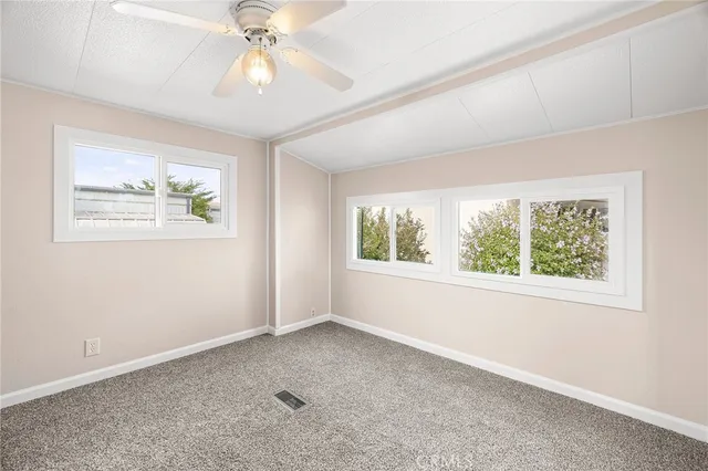 a view of an empty room with window and chandelier fan
