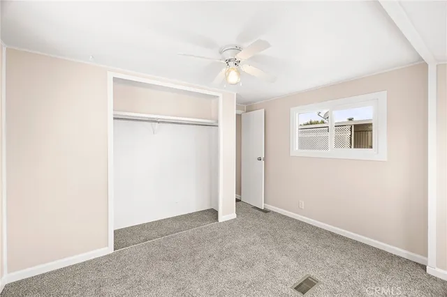 an empty room with a ceiling fan and a window