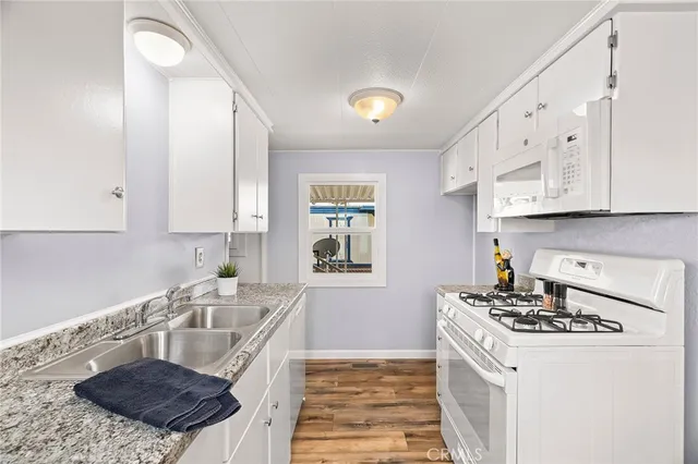 a kitchen with granite countertop a sink a stove and cabinets