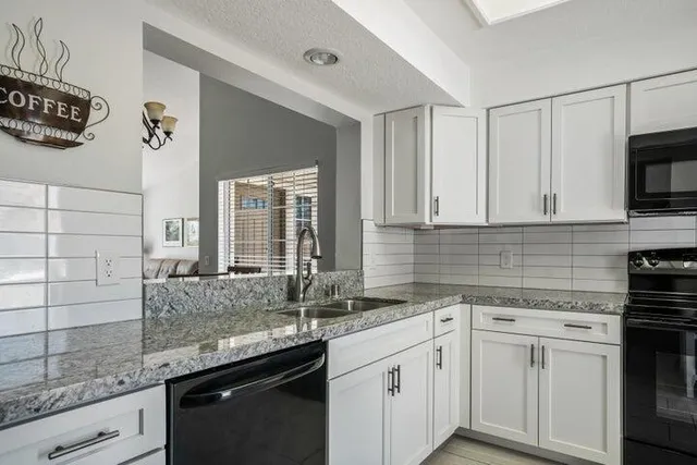 a kitchen with granite countertop a sink a stove and cabinets