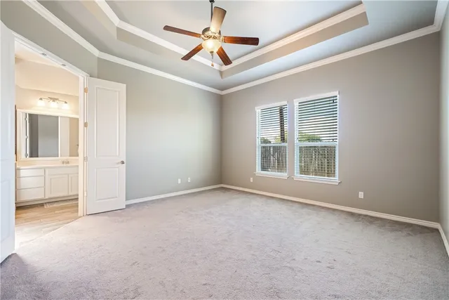 an empty room with chandelier fan and windows