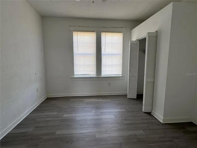 an empty room with wooden floor and windows