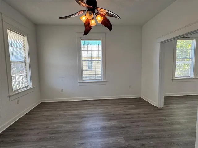 a view of an empty room with wooden floor and windows