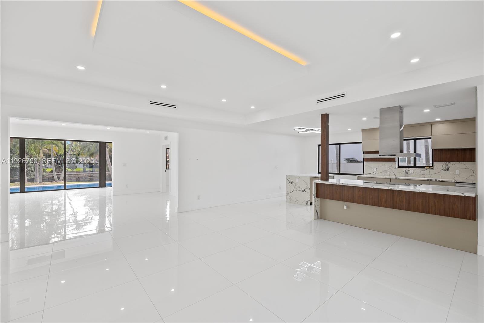a large white kitchen with a refrigerator a sink and a large window