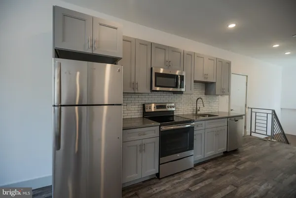 a kitchen with stainless steel appliances granite countertop a refrigerator a stove a sink and a microwave