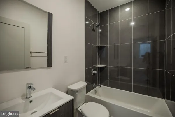 a bathroom with a bathtub shower sink vanity and toilet